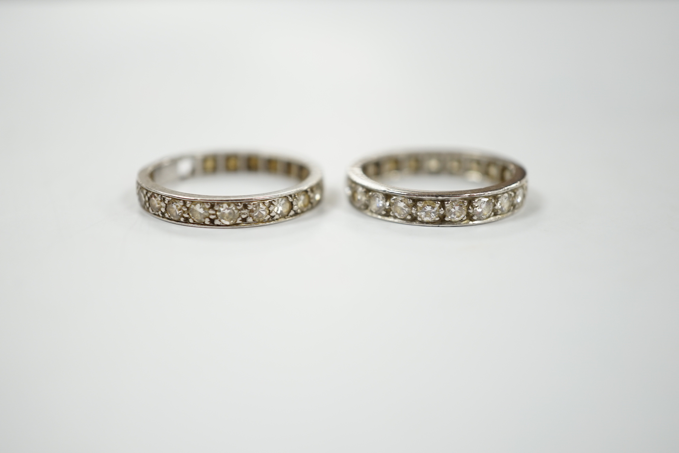 Two white metal and diamond set full eternity rings, one with cut shank and stone missing, sizes L & P, gross weight 7.7 grams.